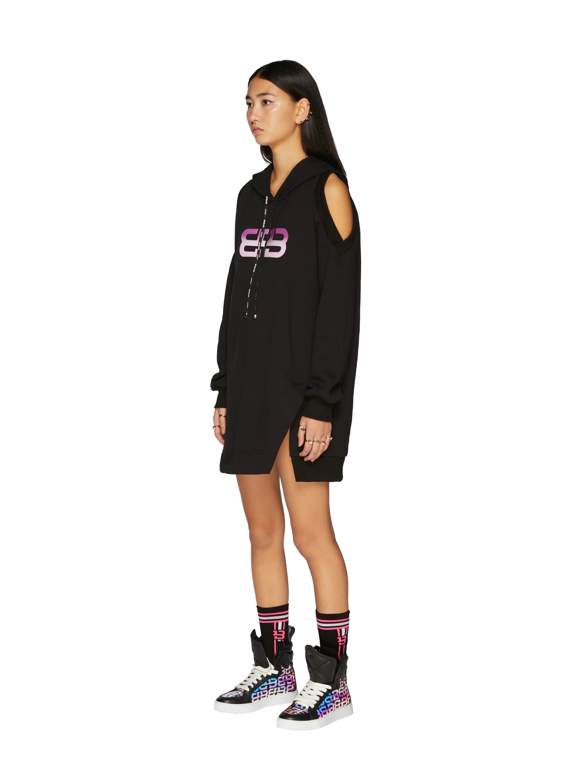 Black Monogram Cotton Dress with cut-out shoulders and gradient logo, paired with bold graphic sneakers and sporty socks.