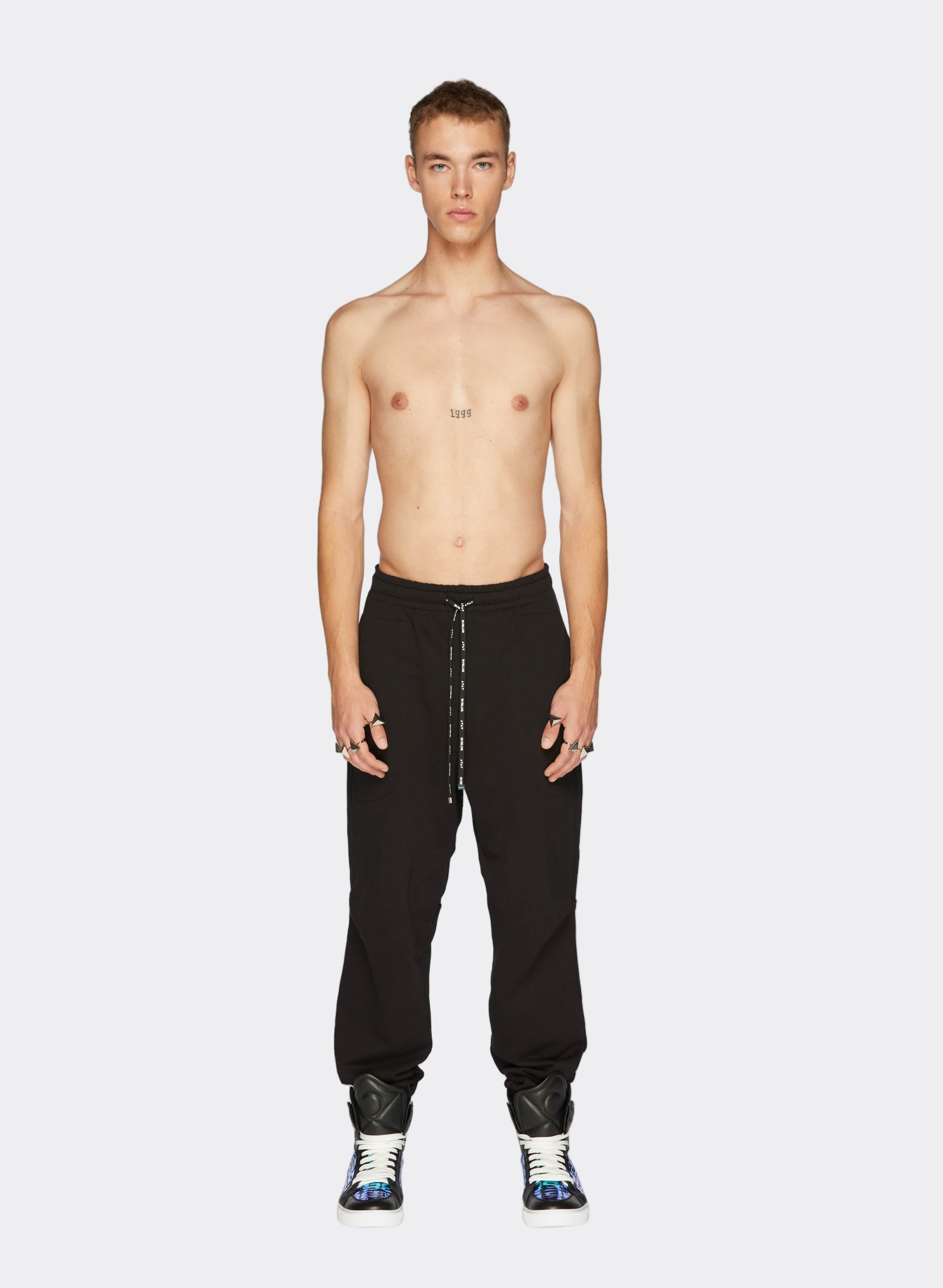 Model wearingLogo track joggers with drawstring waist and sleek black 3D Logo Iridescent Sneakers, showcasing contemporary urban style