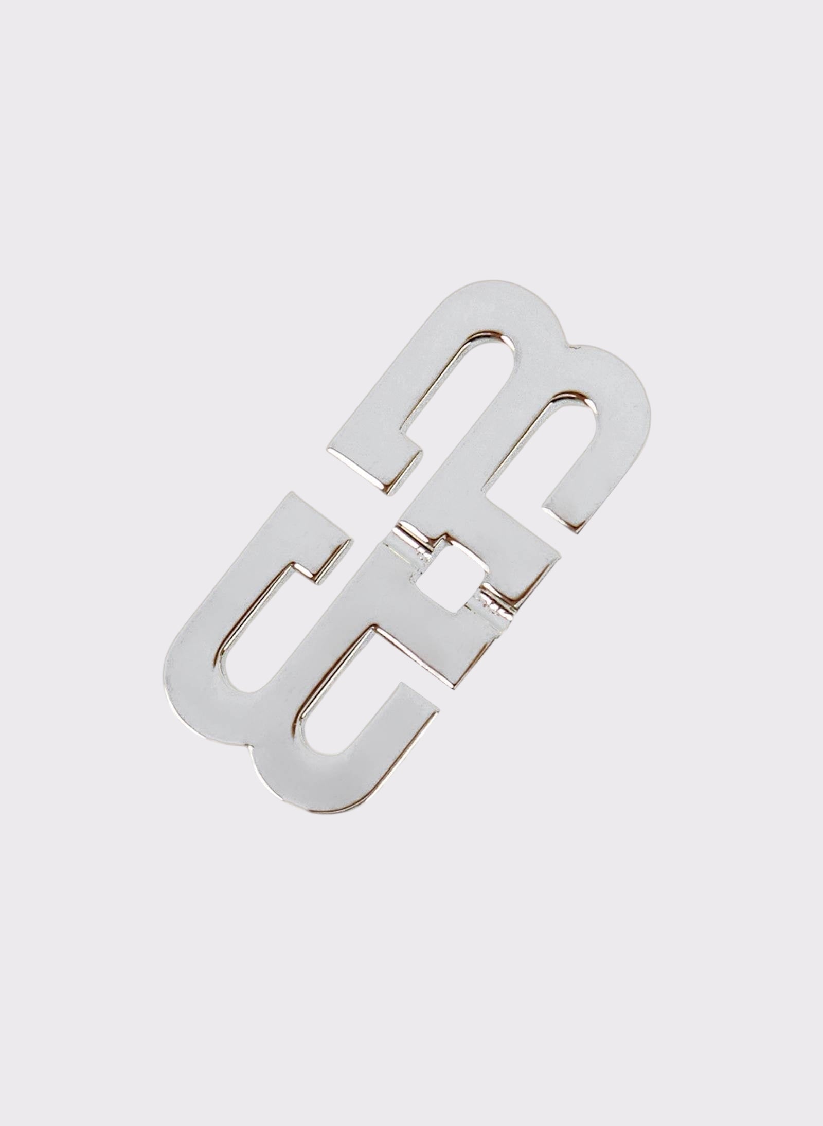 A silver-tone mono earring with a geometric design and a mirror effect finish, featuring a logo in the middle.