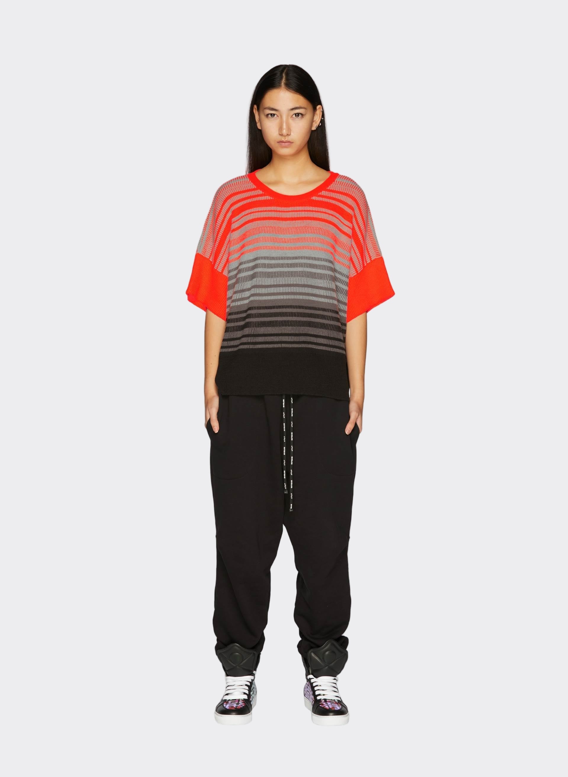 Knit Fluo Top with red, gray, and black stripes, paired with relaxed black joggers and stylish sneakers - Byblos contemporary flair.